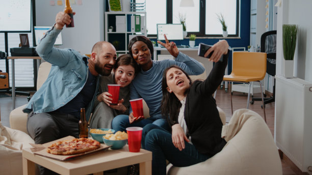 多民族的同事们喝着饮料，吃着零食，玩得很开心图片下载