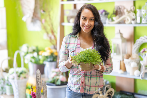 花店老板捧着一个花盆，里面放着草药。图片下载
