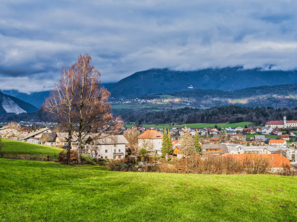 斯洛文尼亚，卡姆尼克，多云的下午，卡姆尼克村的房子，郁郁葱葱的草地和山峦图片下载