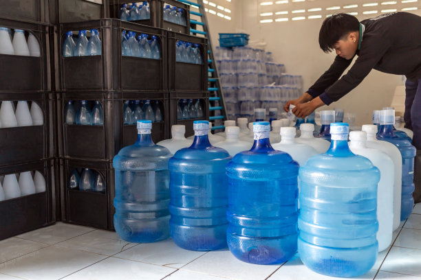 塑料大瓶或白色和蓝色加仑的纯净饮用水在生产线内准备销售。饮水厂，小本经营图片下载