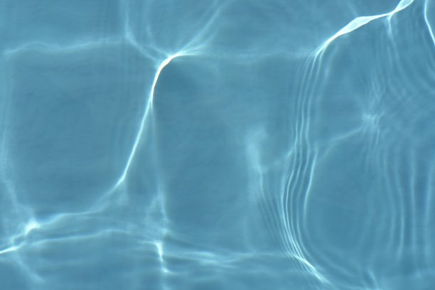 蓝蓝的水面上泛起涟漪。散焦模糊透明蓝色透明平静水面纹理与飞溅和气泡。水波与闪亮的图案纹理背景。图片下载