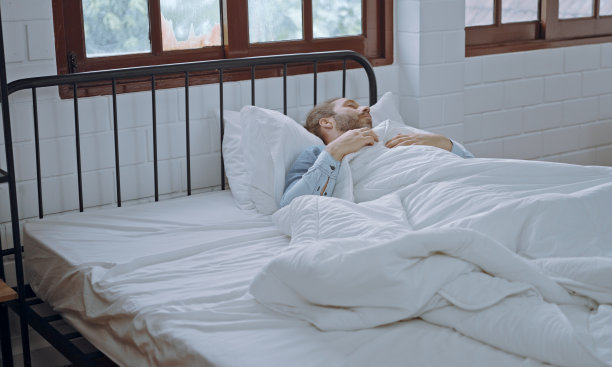男性睡在家里卧室的床上。图片下载