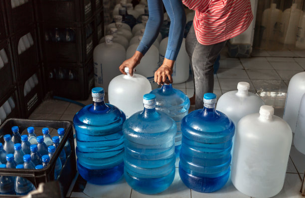 工人们推着塑料大瓶或白色和蓝色加仑的纯净饮用水进入生产线，准备销售。饮水厂，小本经营图片下载