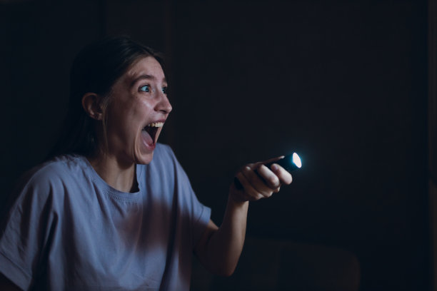 女人害怕在黑暗中手持手电筒，害怕暴力犯罪抢劫。图片下载