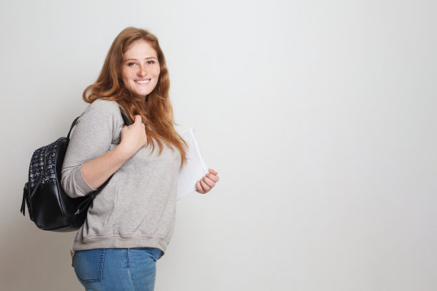 快乐的女学生站在白色的工作室墙上横幅的背景图片下载