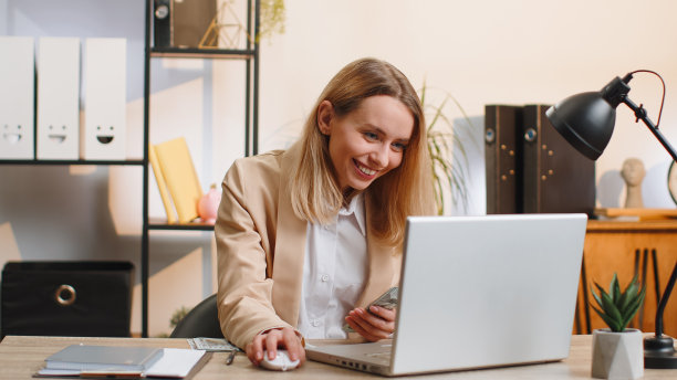 富有的女商人穿着西装，在笔记本电脑上工作，数钱，计算收入，收入，利润图片下载