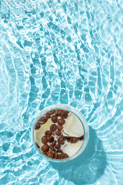 一杯加了咖啡豆和牛奶的冰块，浸在波纹水中。夏日晨饮的主意。副本的空间。冷饮的主意。图片下载