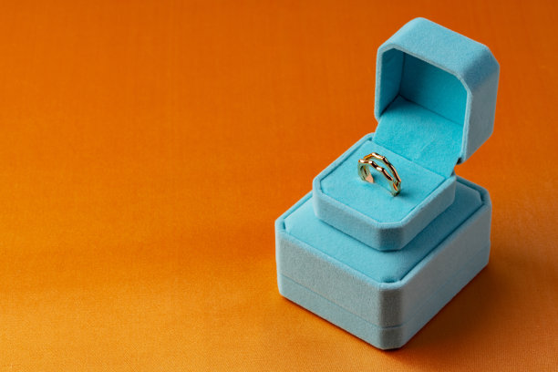 金戒指在首饰盒上的橙色背景图片下载