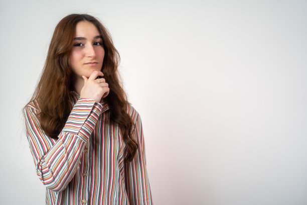 在灰色的墙壁背景上，一个快乐的少女在梦中独自摆姿势。手靠近脸。深思熟虑的严肃聪明的表情，深思熟虑的回答，怀疑和怀疑图片下载
