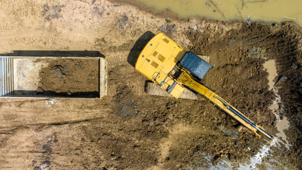 在自卸卡车中挖掘土壤，以建造一个池塘，用于储存旱季农业用水，鸟瞰图图片下载