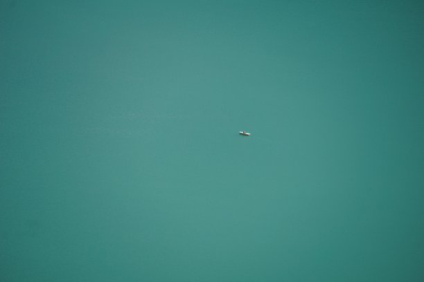 湖上一艘船的俯视图。绿松石湖上的船，无人机拍摄的照片。船在湖上俯瞰。无人机拍摄的泽尔湖。小船上的湖顶景色。高空的一架无人机正在拍摄湖面上一艘孤独的船。图片下载