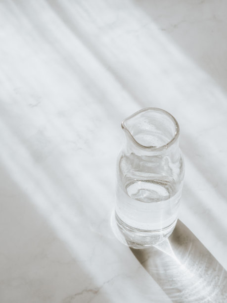 阴影中的厨房木桌上放着一瓶水。图片下载