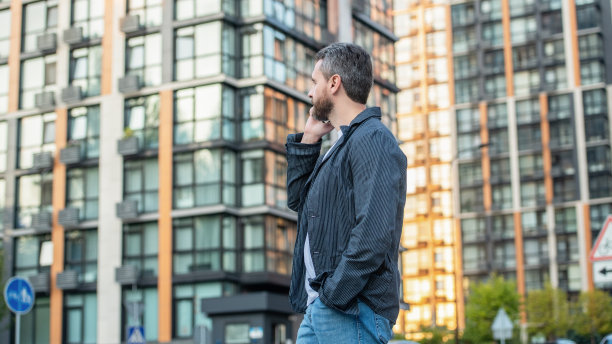 一个人用手机看远处的户外。有人在街上打电话。图片下载