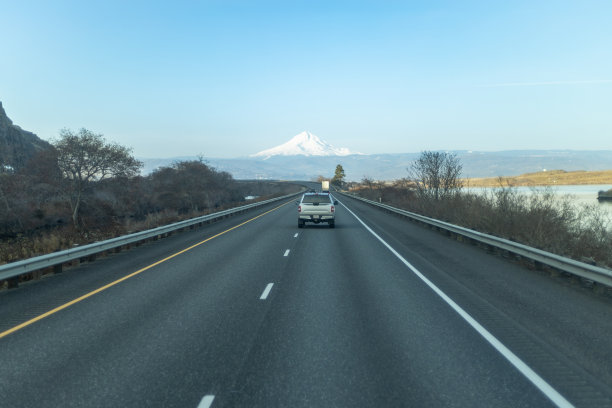 一辆汽车在高速公路上行驶，背景是一座山。图片下载