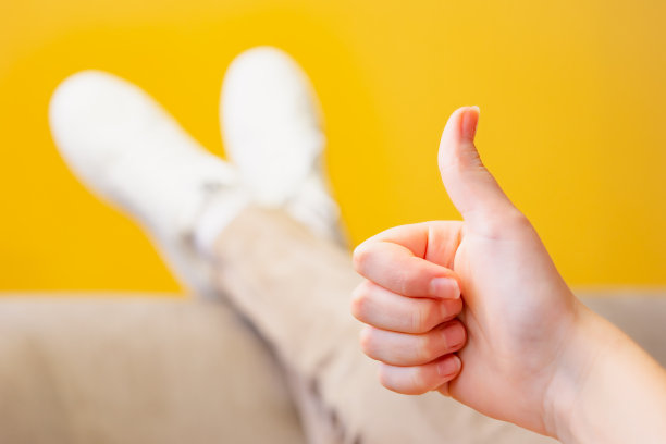 女孩的手在黄色背景上做ok的手势图片下载