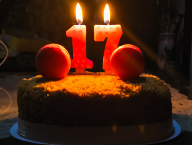 生日蛋糕与17号蜡烛在黑暗的背景光。图片下载