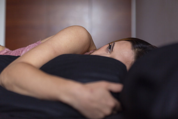 一个拉丁女人躺在家里的床上，在孤独中带着一种失落和悲伤的表情图片下载