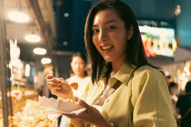 亚洲女人喜欢在夜市吃薯条。游客亚洲博主女性快乐的游客美丽的女性与传统泰国曼谷美食。图片下载