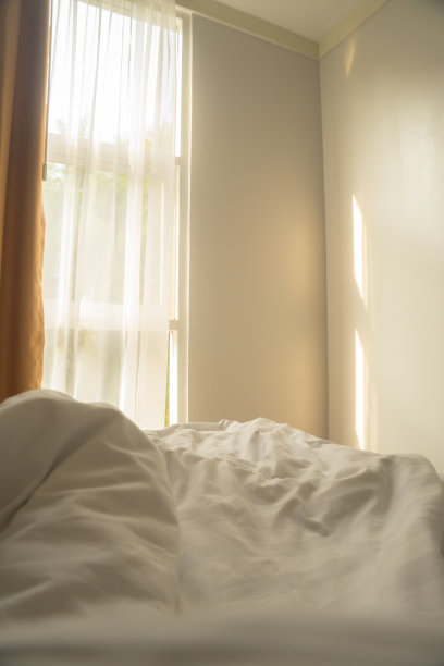 凌乱的床罩带着阳光从窗户射进白色的房间图片下载