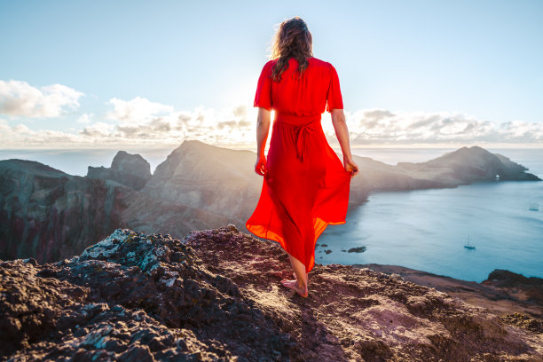穿着红色连衣裙的赤脚妇女享受着火山岛山麓和海洋的早晨气氛。欧洲葡萄牙马德拉岛的<s:1> o loureno。图片下载