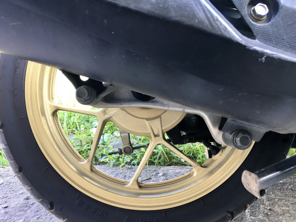 绿色草地背景下的排气管和金色摩托车轮毂特写照片图片下载