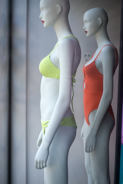 在一家时装店的陈列室里，模特穿着绿色和橙色的泳衣图片下载