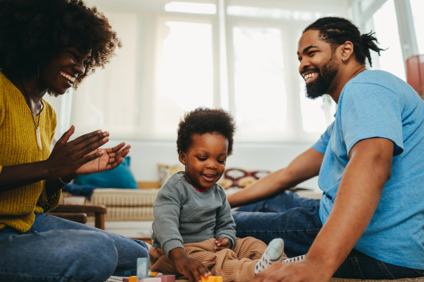 一个快乐的非裔美国小男孩正在解决一个教育游戏，他的父母在鼓掌和鼓励他。图片下载