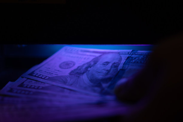 紫外线灯下美元的特写。用验钞机检查一美元纸币。图片下载