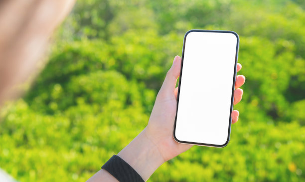 女人站在花园的桥上，手里拿着智能手机的空白屏幕模型，拿着你的屏幕放广告。图片下载