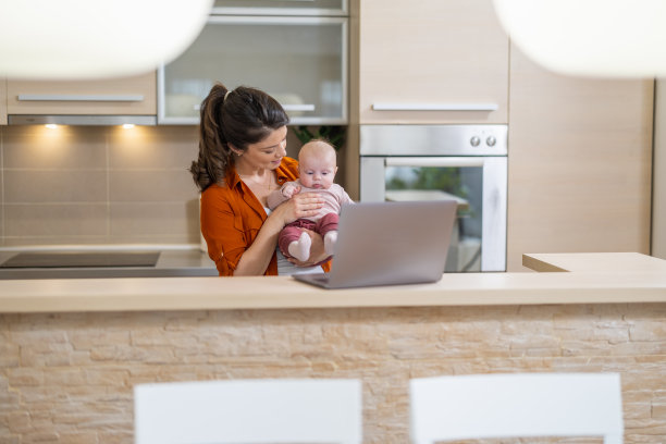 母亲带着孩子在厨房使用笔记本电脑图片下载