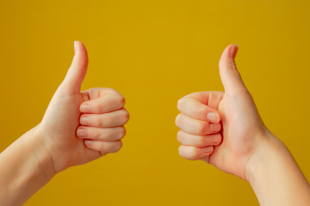 在黄色背景上，女孩举着两个大拇指图片下载