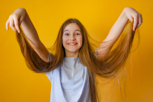 笑着的长发小女孩握着她的头发图片下载