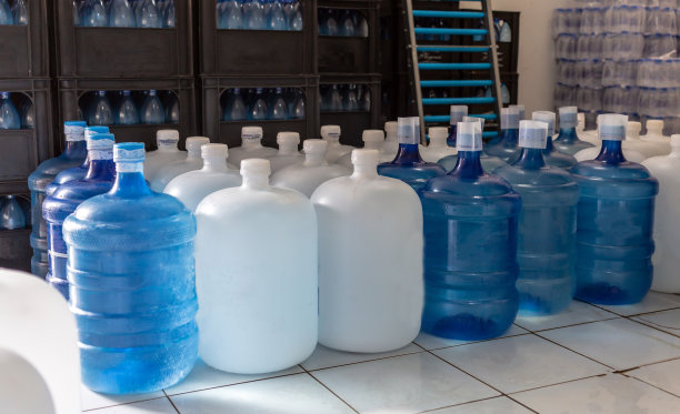 塑料大瓶或白色和蓝色加仑的纯净饮用水在生产线内准备销售。饮水厂，小本经营图片下载