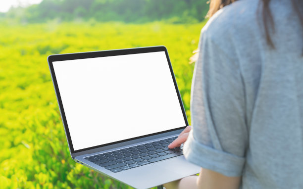 女人站着，手拿着笔记本电脑的空白屏幕模型，拿你的屏幕放广告。在日常生活的任何地方通过互联网工作的概念。图片下载