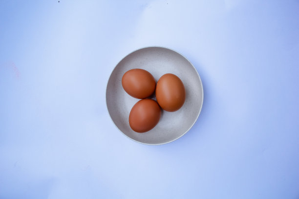 三个鸡蛋放在一个白色背景的盘子里图片下载