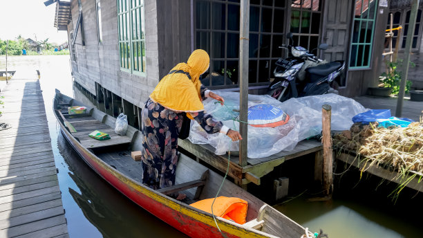 在河边的一所房子里，一名漂浮的市场女士正在整理她的货物图片下载