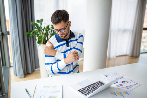 年轻的商人加班工作，在家里使用笔记本电脑时感到肩膀疼痛图片下载