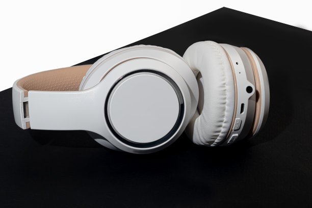 深色背景上的米色无线耳机。听歌配件。隔离。图片下载