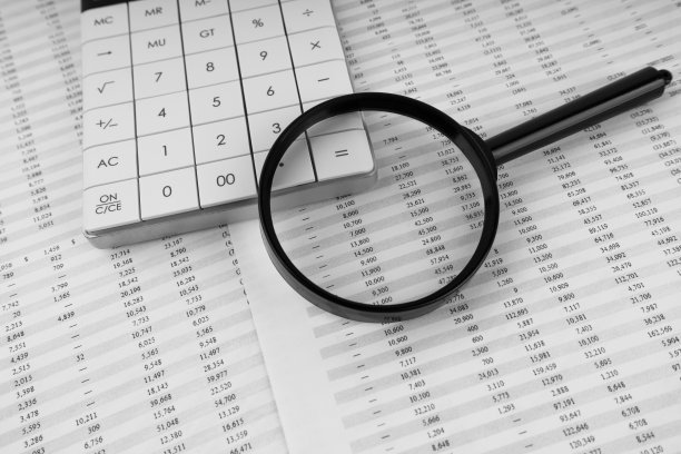 财务文件的计算器和放大镜。图片下载