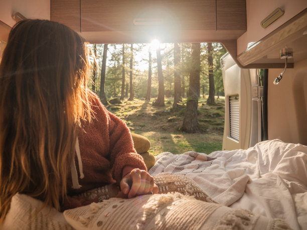 女人放松在她的货车后面俯瞰森林日落图片下载