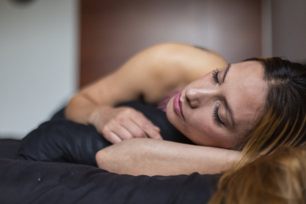 一个拉丁女人躺在家里的床上，在孤独中带着一种失落和悲伤的表情图片下载