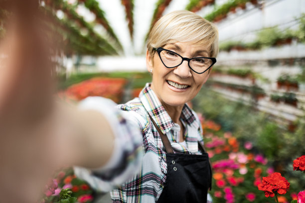 一位微笑的年长女性在温室里自拍图片下载