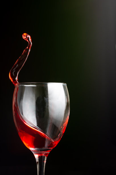 玻璃杯里的小瓶酒，深色背景图片下载