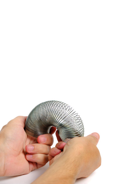 金属弹簧抗应力玩具，弹簧，手白色背景。图片下载