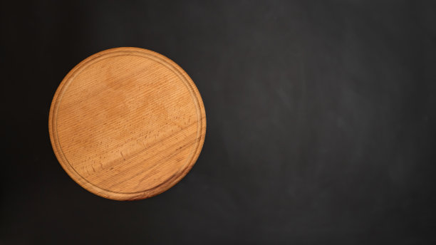 圆形木板上的黑暗背景从上面看。烹饪用砧板图片下载