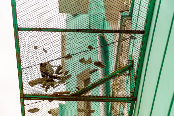 建筑外部装饰的旧混凝土元素位于由金属网制成的保护罩上图片下载