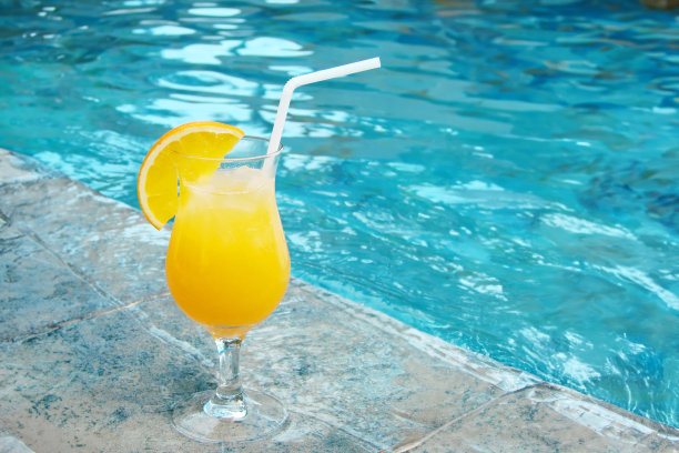 在游泳池边用吸管喝橙汁图片下载