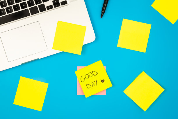 笔记本电脑，蓝色背景上有许多便利贴，平铺。图片下载