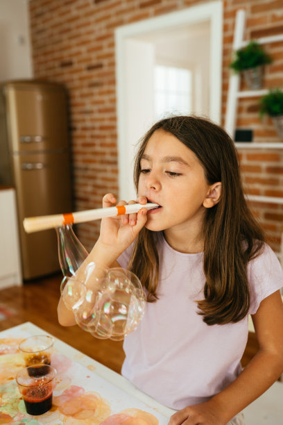 女孩用稻草吹泡泡，在纸上画画图片下载