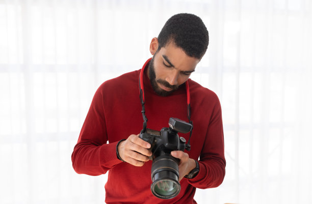 年轻帅气的专业摄影师使用数码相机图片下载